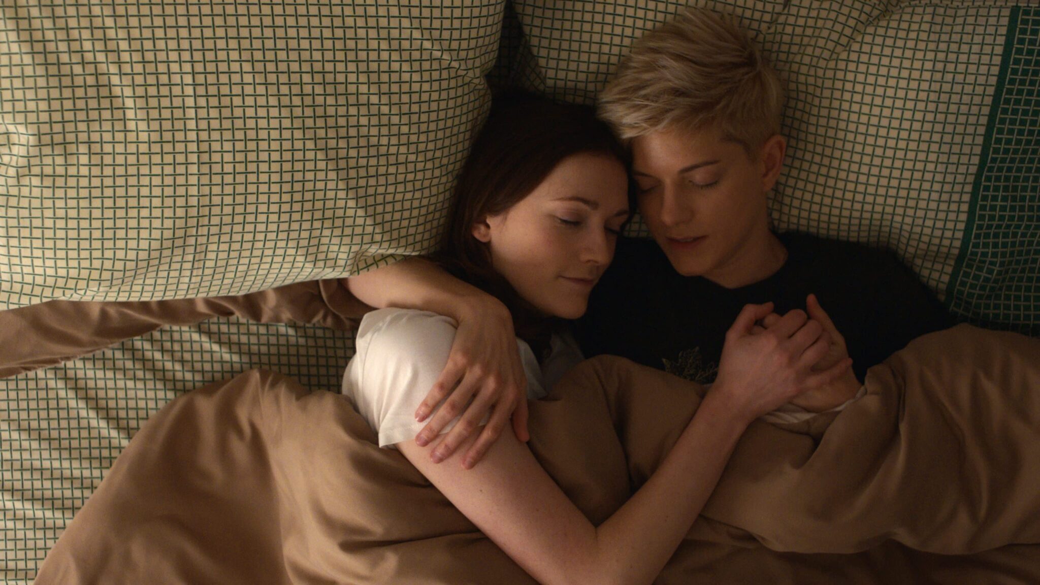 Image from Feel Good of Mae Martin and Charlotte Ritchie cuddling together in a bed