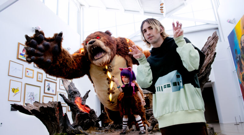 Photo of Porter Robinson posing with League of Legends figures