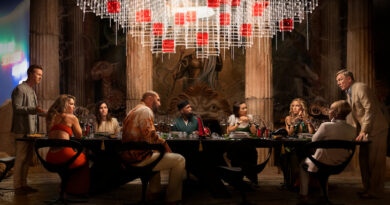 Photo from Glass Onion of guests sitting at a table while Daniel Craig yells at them