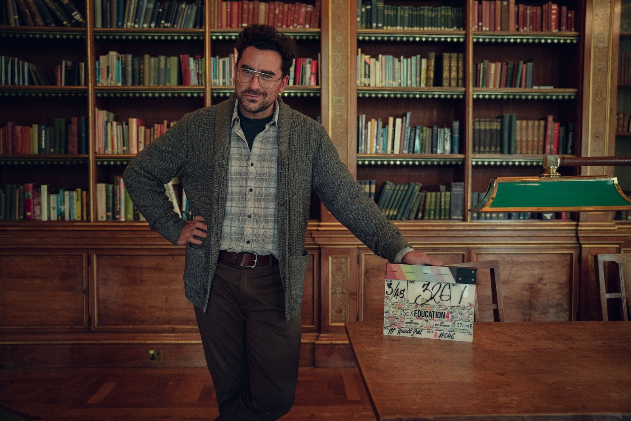 Photo of Dan Levy leaning on a desk from season 4 of Sex Education