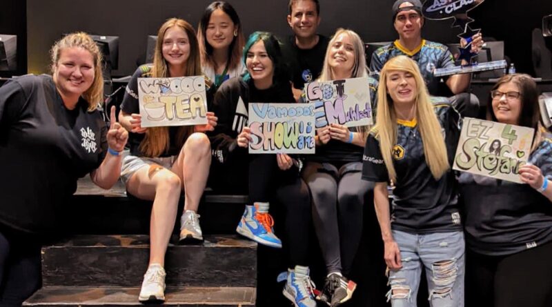 Photo of the Evil Geniuses roster and their support staff holding the Astral Clash trophy and several signs with slogans