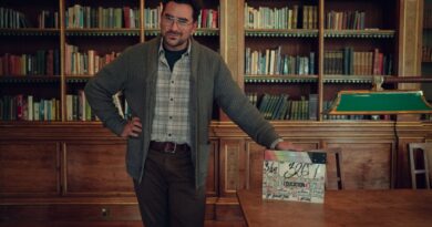 Photo of Dan Levy leaning on a desk from season 4 of Sex Education