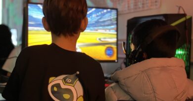 Kids playing games at a computer. One kid has a Tenstar logo on the back of their shirt