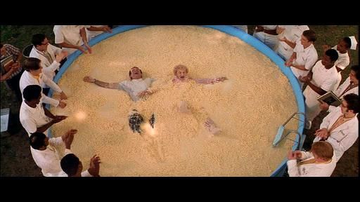 Screenshot of Robin Williams as Patch Adams swimming in a pool of noodles with an old lady