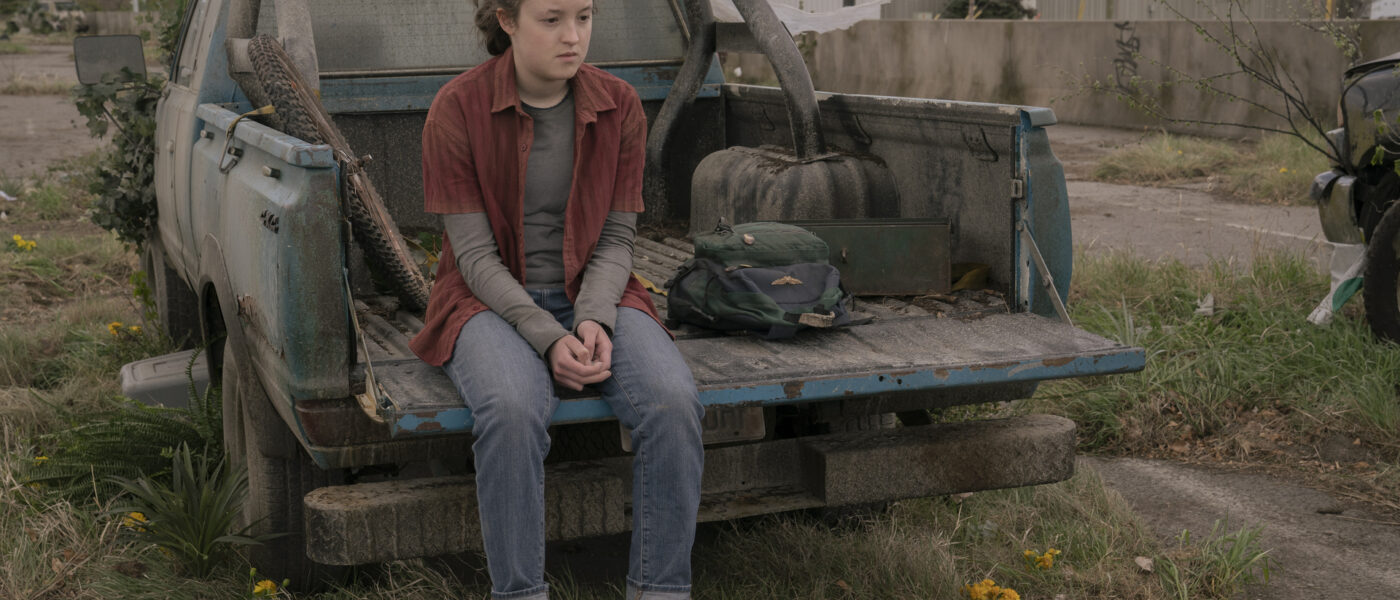 Bella Ramsey as Ellie in HBO's The Last of Us sitting on the bed of a dirty pickup truck